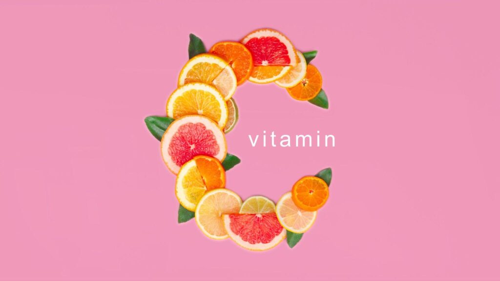 daily vitamin c Various slices of grapefruit, orange, and lemon arranged to form a large letter "C" with the word "vitamin" centered inside, set against a solid pink background.