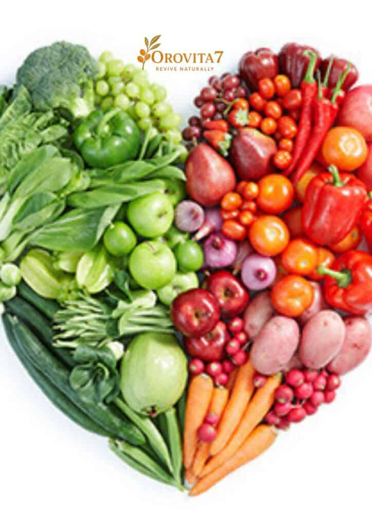 Fresh green and red vegetables and fruits arranged in a large heart shape to represent natural heart health.