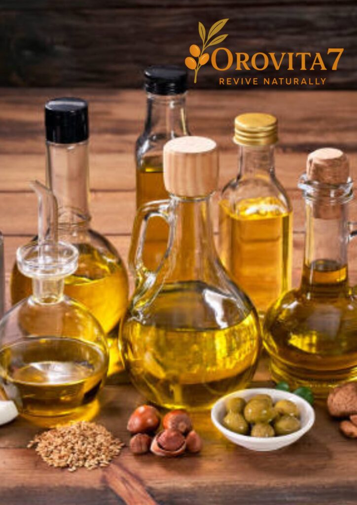 Multiple glass bottles of various oils arranged on a wooden surface with olives, nuts, and seeds in the foreground.