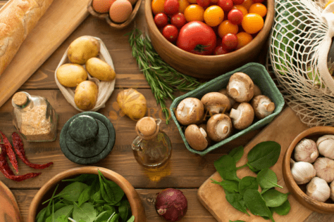 An overhead view of a wooden table featuring organic mushrooms, tomatoes, spinach, and garlic, perfectly aligning with a natural wellness lifestyle.