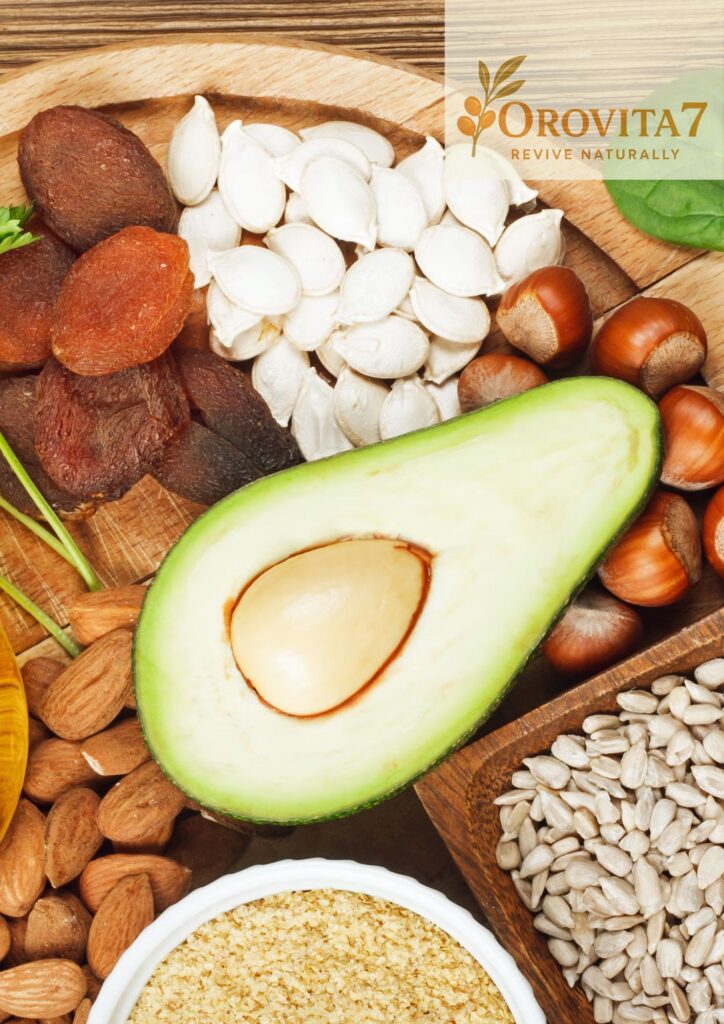A close-up of nutrient-dense foods including an avocado half, nuts, and seeds on a wooden tray with an OroVita7 logo in the corner.