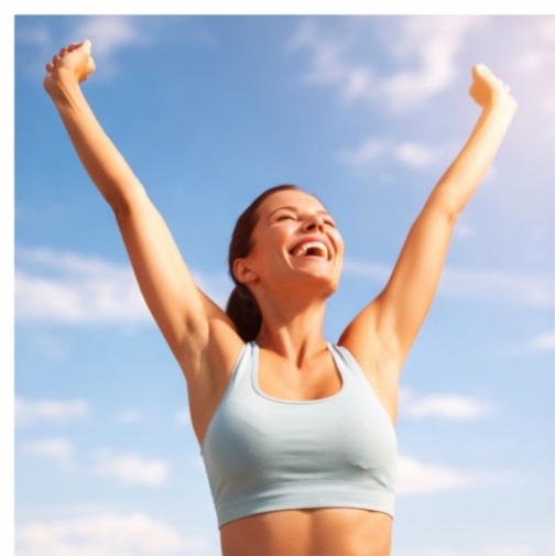 A young woman in light blue athletic wear standing against a clear blue sky with her arms raised in a "V" shape, eyes closed and smiling joyfully, representing health and achievement.