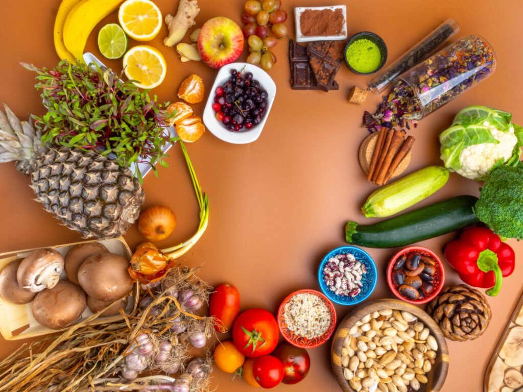 Variety of fresh fruits, vegetables, nuts, and natural foods arranged on a surface representing balanced nutrition and healthy eating habits
